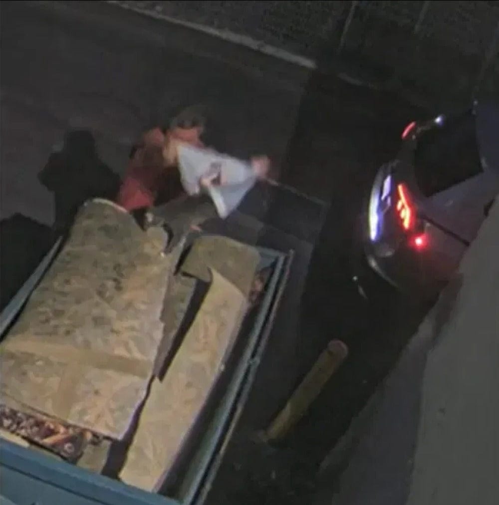 Grainy nighttime surveillance footage shows a man holding a white bag beside a dumpster and parked car.